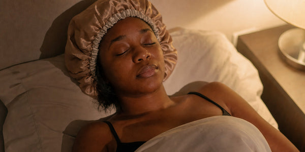 Femme aux cheveux bouclés portant un bonnet en satin pour la nuit